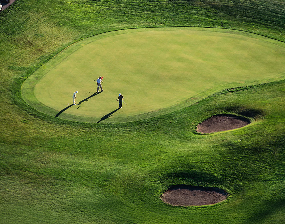 Aerial shot of 3 people at the golf course